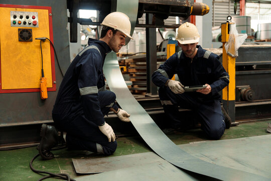 Engineers and staff are inspecting the assembly line system in a metal sheet and metal roofing manufacturing plant.