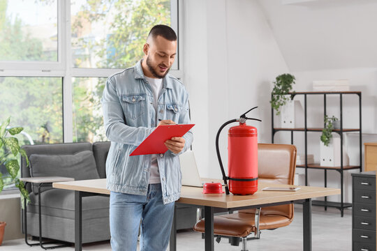 Fire safety inspection and workplace compliance, man checking fire extinguisher equipment with a clipboard in a modern office environment