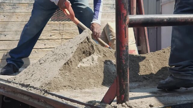 Male worker unloading sand from a flatbed truck