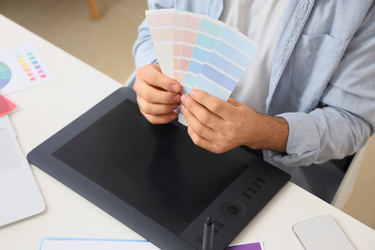 Male interior designer with color palettes at table in office, closeup