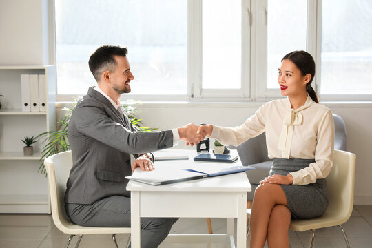 Human resources manager interviewing shaking hands with applicant in office