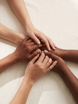 Hands woven together in support among diverse people, expressing unity and comfort during shared moment