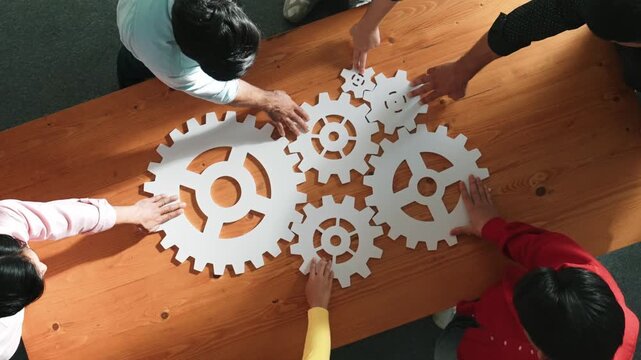 Top view of business people gathering white gear together at meeting table. Group start up team in casual cloth working together connecting cog together. Cooperate, teamwork,togetherness. Convocation.