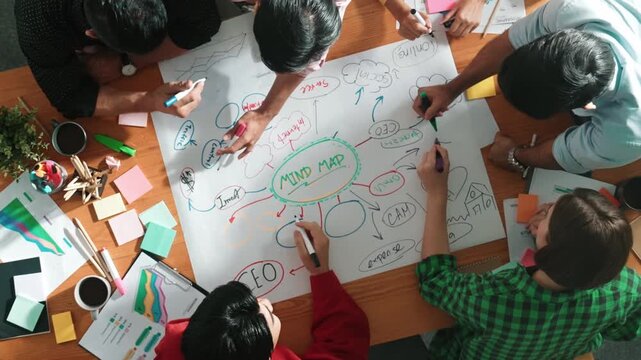 Group of business people writing and making mind map to brainstorming marketing idea at meeting. Top aerial view of investors sharing plan or strategy by using sticky notes. Time lapse. Convocation.