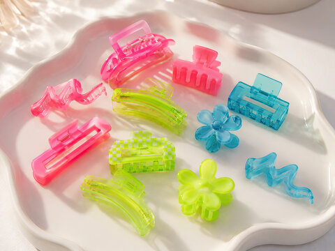 A collection of brightly coloured hair clips rests on a white porcelain plate