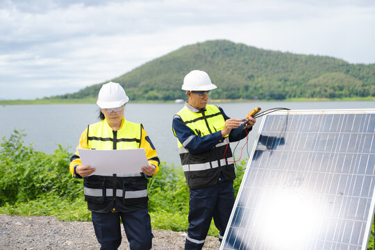 Professional engineers in safety gear using tools to install and maintain photovoltaic solar panels at a clean energy power