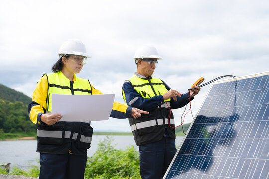 Professional engineers in safety gear using tools to install and maintain photovoltaic solar panels at a clean energy power