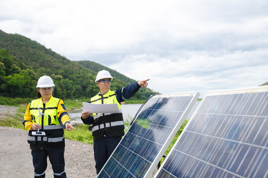 Professional engineers in safety gear using tools to install and maintain photovoltaic solar panels at a clean energy power