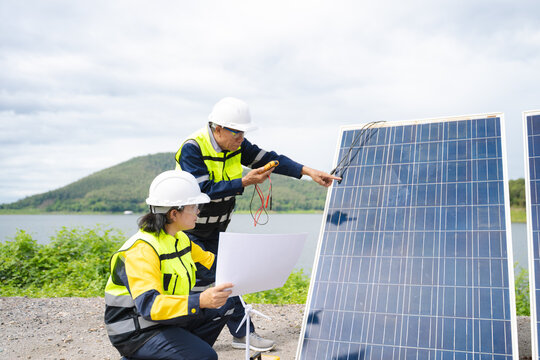 Professional engineers in safety gear using tools to install and maintain photovoltaic solar panels at a clean energy power