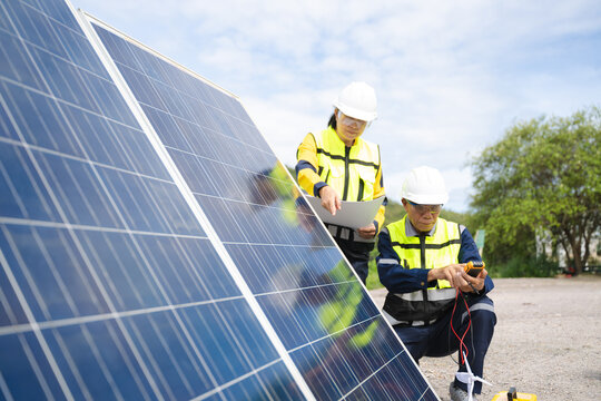 Professional engineers in safety gear using tools to install and maintain photovoltaic solar panels at a clean energy power
