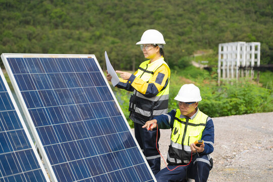 Professional engineers in safety gear using tools to install and maintain photovoltaic solar panels at a clean energy power