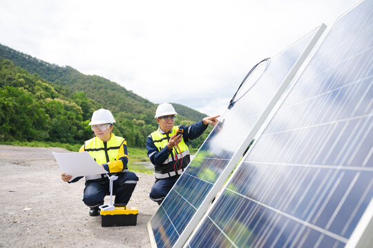 Professional engineers in safety gear using tools to install and maintain photovoltaic solar panels at a clean energy power