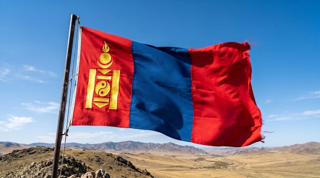 Mongolian flag waving against a clear blue sky over a mountain landscape
