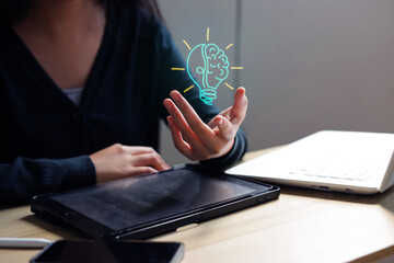 Female Displaying Light Bulb Brain Graphic Next to Electronic Devices © Queenmoonlite Studio