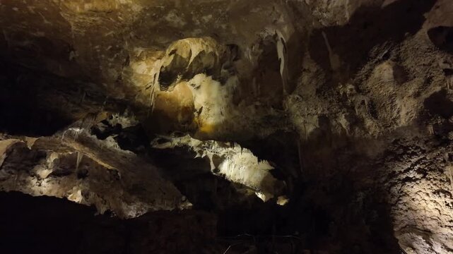 Illuminated cave interior with stalactites and rock formations.