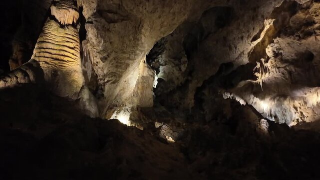Illuminated cave interior with stalactites and stalagmites.
