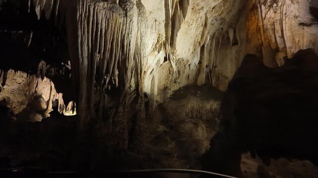 Lit limestone cave with stalactites and stalagmites.
