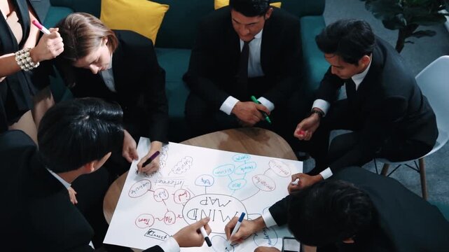 Top view of skilled diverse business people planning project by using mind map to brainstorm marketing idea. Smart start up team working together to draw mind map. Creative workplace. Directorate.