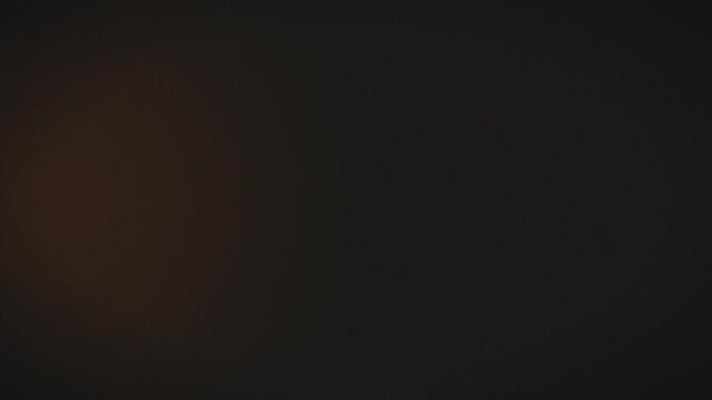 Cinematic soft orange light leak film overlay texture on dark background for vintage video effects and nostalgic aesthetic photography backdrops