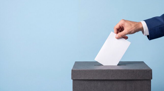 Professional person in a blue suit putting a white ballot paper or envelope into a black box for voting, feedback submission, or suggestion process isolated on a light blue background.