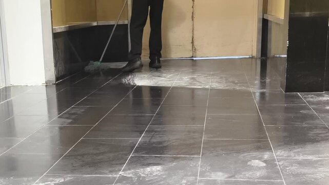 Professional cleaner mopping hallway floor with wet mop
