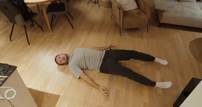 Man experiencing an epileptic seizure, shaking on the floor at home.