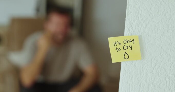 Sad man crying in the background with an &ldquo;It&rsquo;s Okay to Cry&rdquo; supportive message in focus.