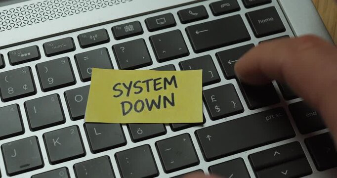 Frustrated user repeatedly pressing the Enter key on a laptop with a System Down warning.