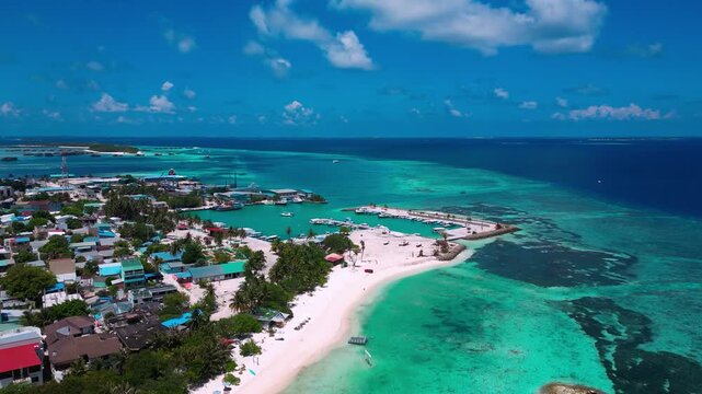 Drone shot of inhabited local island town with white sandy coastline surrounded by turquoise coral lagoon. Great background for travel, culture, and island promo.Himmafushi island.Maldives