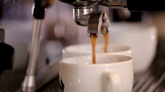 ​Espresso coffee pouring from a professional machine into white cups  
