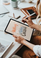 Woman drawing holiday greetings typography on tablet © Rawpixel.com
