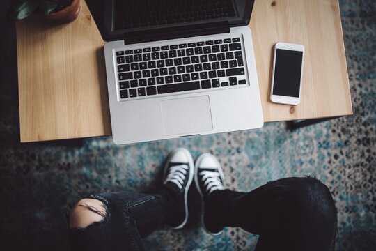 Teenager using laptop on wooden table, aerial view