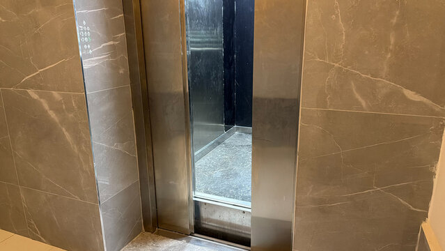Broken elevator stopped above floor level with open doors, showing a dangerous gap and malfunction in a residential building.