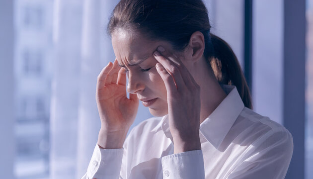 Stressed Woman Experiencing Headache and Mental Fatigue While Sitting Indoors