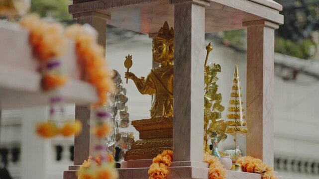 Close-up of a golden phra phrom shrine statue with traditional flower garlands in bangkok
