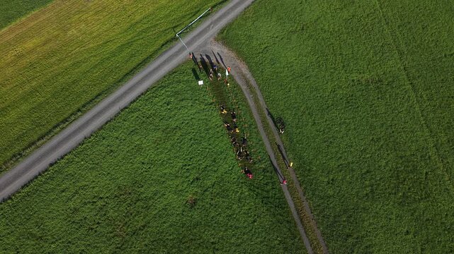 Top-down aerial view of participants crawling beneath a low obstacle during a demanding outdoor challenge, highlighting determination, endurance and overcoming physical barriers.