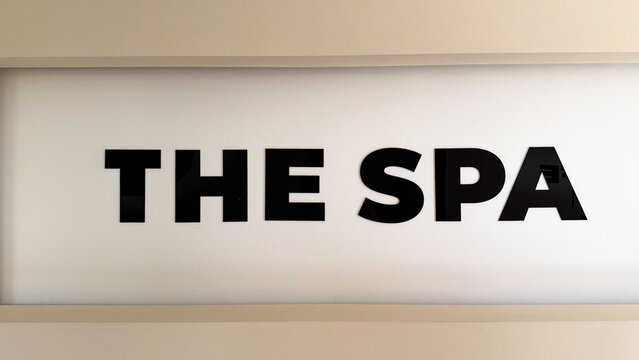 Modern spa sign with black lettering on a minimalist white wall in a hotel or residential complex wellness area.