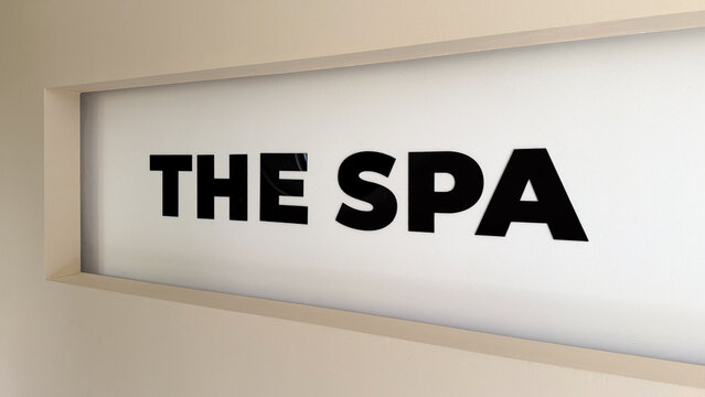 Modern spa sign with black lettering on a minimalist white wall in a hotel or residential complex wellness area.