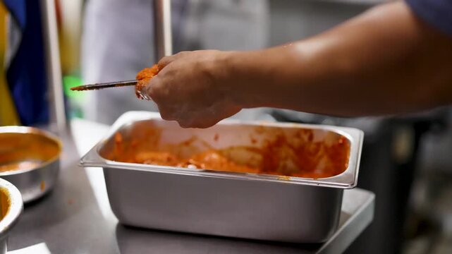 Chef Threading Marinated Chicken Tikka Onto Metal Skewer in Kitchen
