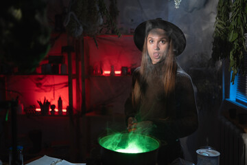 realistic witch brewing a potion in cauldron showing tongue sticking looking at camera. Blend of everyday life with traditional witchcraft, magic and mystical atmosphere © Andrii Lysenko