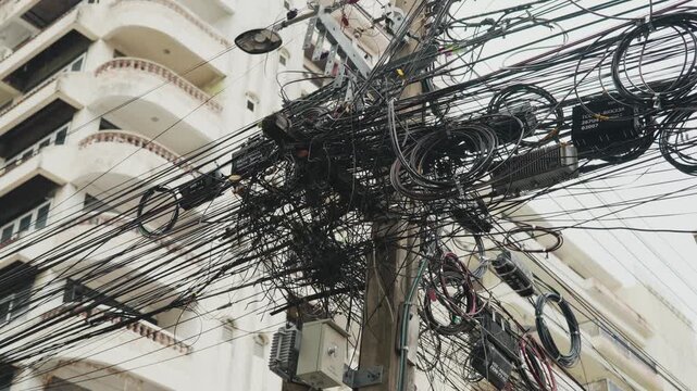 Chaotic tangle of electrical and communication cables on a utility pole in a developing country