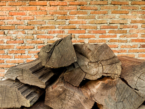 Pile of Chopped Firewood Logs in Front of Brick Wall