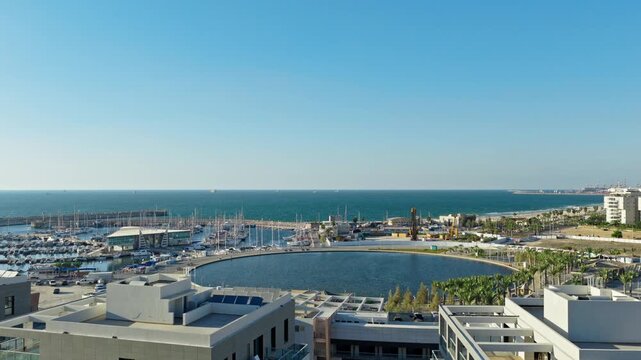 Aerial drone shot of Ashdod marina with yachts, circular artificial lake, coastline, and blue Mediterranean Sea under a clear sky in Israel.
