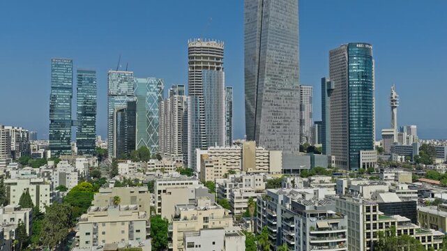 Aerial drone view over residential roofs toward the Sarona Tower, Azrieli Town, and modern high tech skyscraper skyline in Tel Aviv Israel.