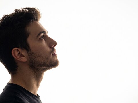 Profile portrait of a man looking up against a bright background