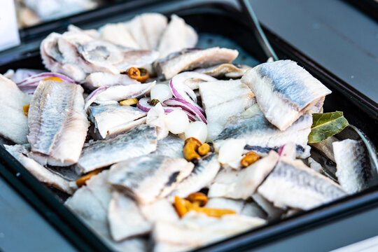 Close-up of a flavorful dish featuring cooked pieces of herrings mixed with saut&eacute;ed onions, carrots, and spices in a street food market