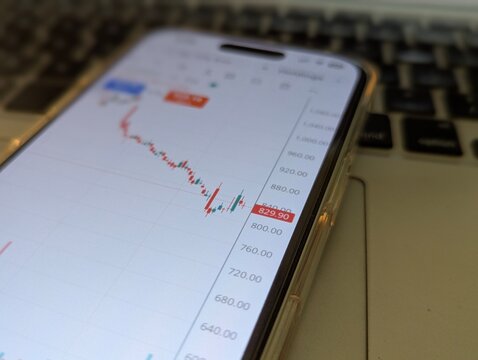Stock market crash chart on smartphone screen resting on laptop keyboard close up photo stock photo
