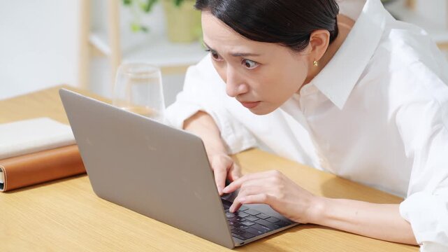 ノートPCにかじりついて見るミドル女性。真剣、仕事、投資、ギャンブル、熱中、集中、仕事、注目、不安