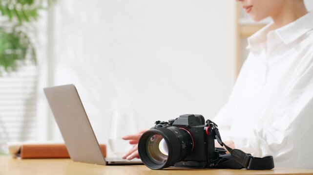 A woman using a camera and a laptop. Photography, editing, shooting, photographer, female photographer, developing, auction, listing.