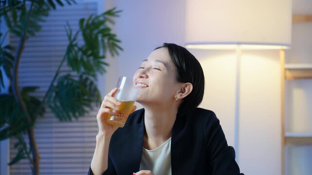 暗い部屋でお酒を飲む女性。ビール、ウイスキー、飲み会、居酒屋、バー、スナック、宅飲み